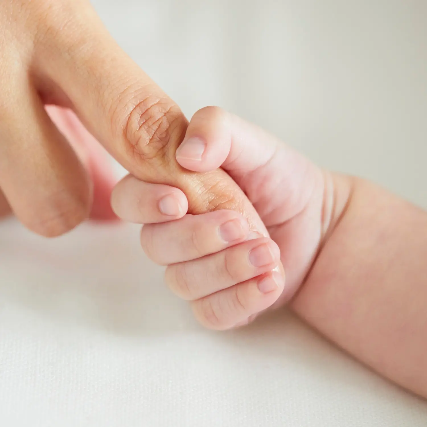 A newborn baby holding their mother's finger beside a poetic definition of "home" on Crumbs and Calendars blog.