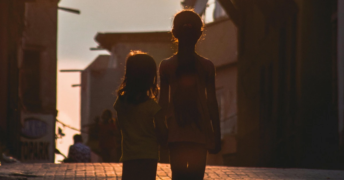 Two children walking through a Filipino street at sunset, symbolizing the quiet role of the eldest child in a Filipino family.