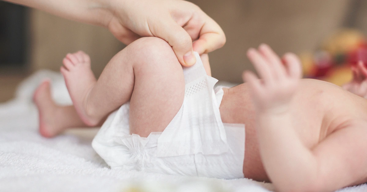 A baby lying on a blanket during a diaper change showing how to care for newborn umbilical cord.