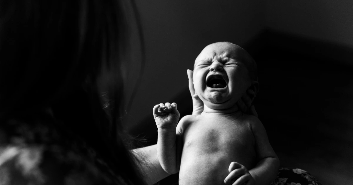 Crying newborn being held by mom during a tough moment when baby won’t stop crying.