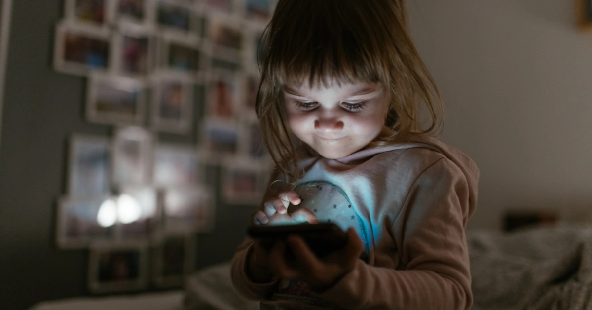 Toddler using a smartphone at night, representing screen time struggles and how to overcome mom guilt.