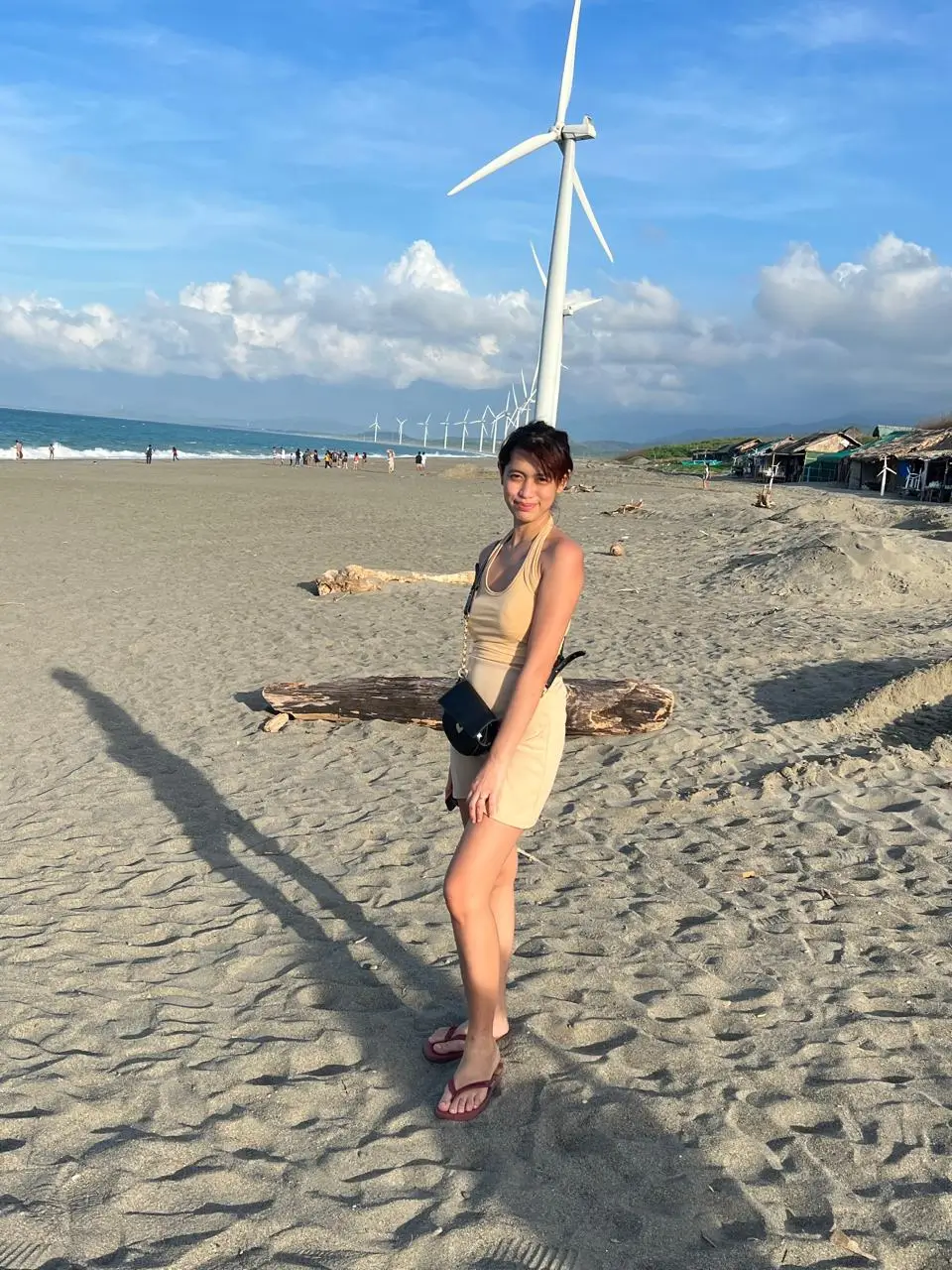 Filipino mom standing on the sandy beach at Bangui Windmills in Ilocos Norte, Philippines.