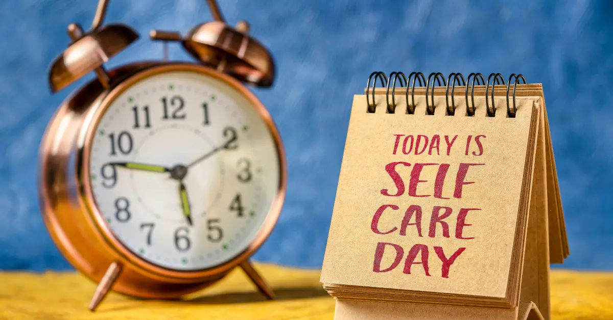 Table calendar with the words today is self care day beside an alarm clock, representing self care for moms and the importance of finding time for yourself