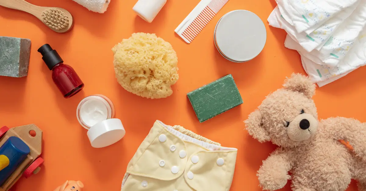 Flatlay of baby essentials including diapers, soap, lotion, sponge, and toy, representing baby products worth buying again.