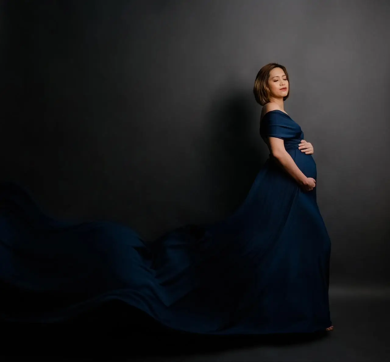 Expecting mom in a flowing navy blue gown during a maternity photo session.