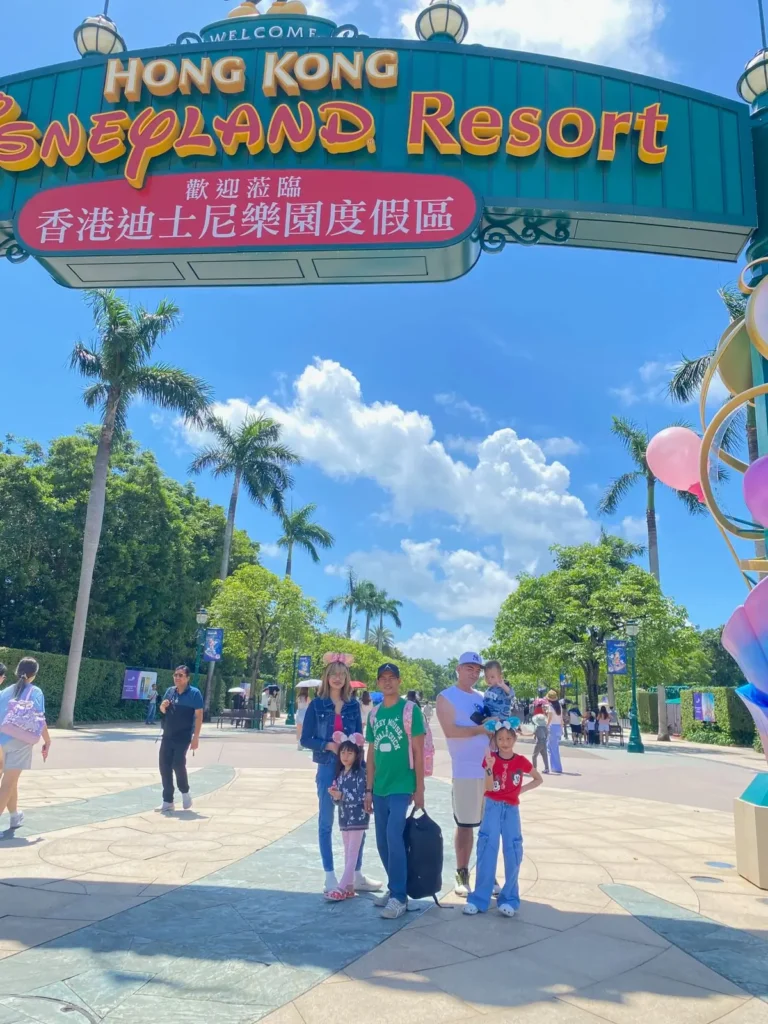 Family photo at the Hong Kong Disneyland Resort entrance with kids on a sunny day.